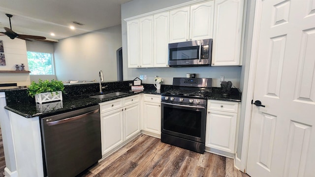 kitchen with stainless steel appliances, a sink, a peninsula, dark wood-type flooring, and ceiling fan
