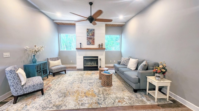 living area featuring ceiling fan, wood finished floors, baseboards, and a fireplace