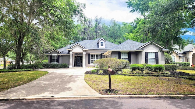 ranch-style house featuring stucco siding, concrete driveway, a front yard, and a shingled roof
