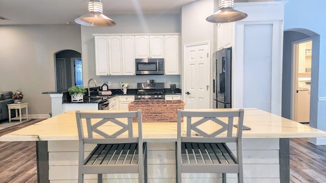 kitchen with appliances with stainless steel finishes, arched walkways, a sink, and a peninsula