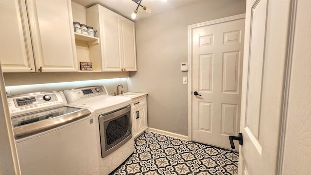 washroom featuring washing machine and clothes dryer, cabinet space, and baseboards
