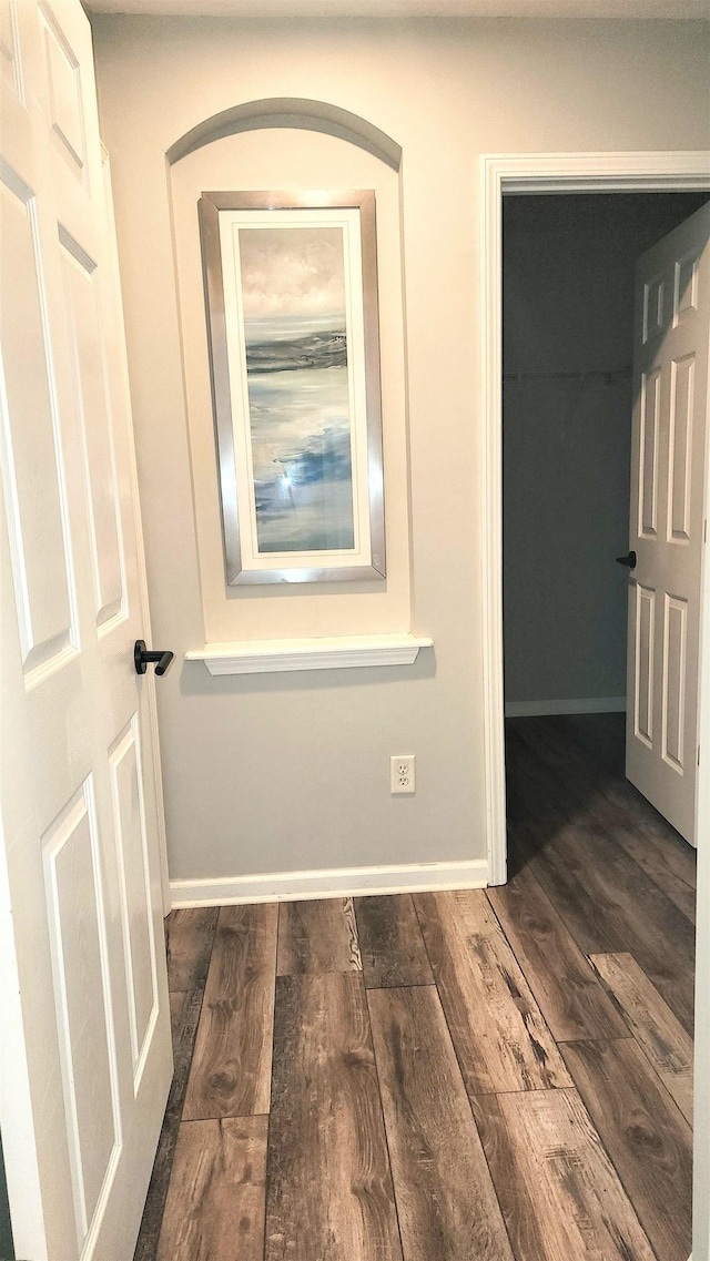 hall with dark wood-style flooring and baseboards