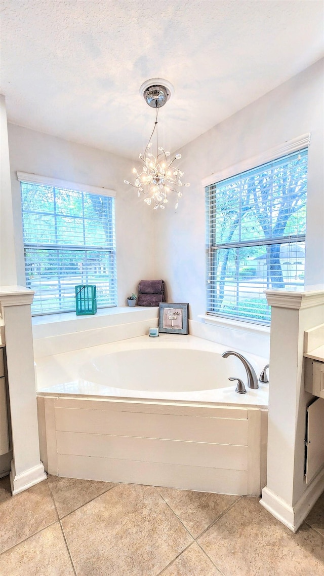 bathroom with tile patterned flooring, a bath, a chandelier, and vanity
