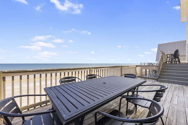 wooden deck with outdoor dining space, a beach view, and a water view