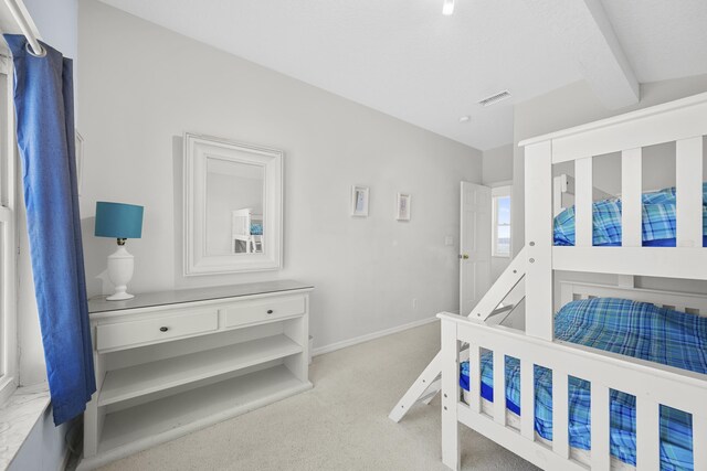 bedroom featuring beamed ceiling, carpet, visible vents, and baseboards