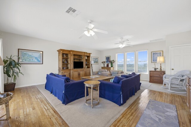 living area with visible vents, light wood-type flooring, and baseboards