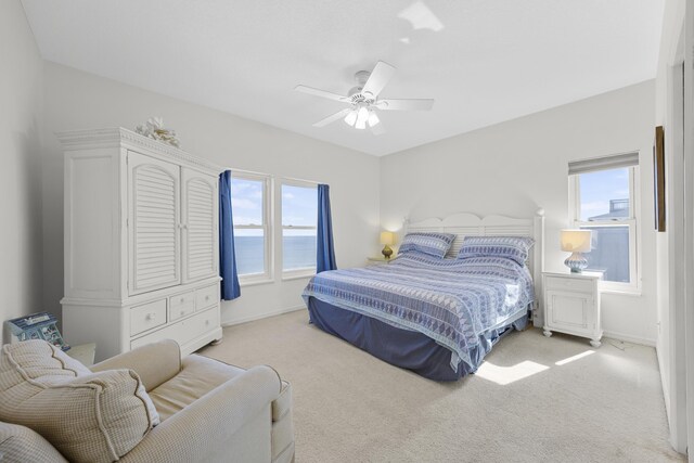 bedroom featuring multiple windows, light colored carpet, and a ceiling fan