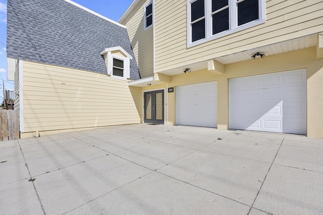 garage with french doors, fence, and driveway