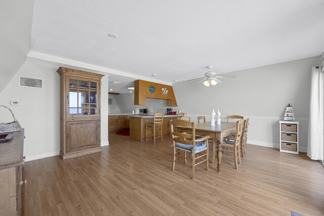 dining area featuring light wood-style flooring, baseboards, visible vents, and ceiling fan