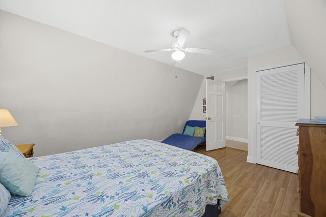 bedroom featuring baseboards, vaulted ceiling, light wood-style flooring, a closet, and a ceiling fan