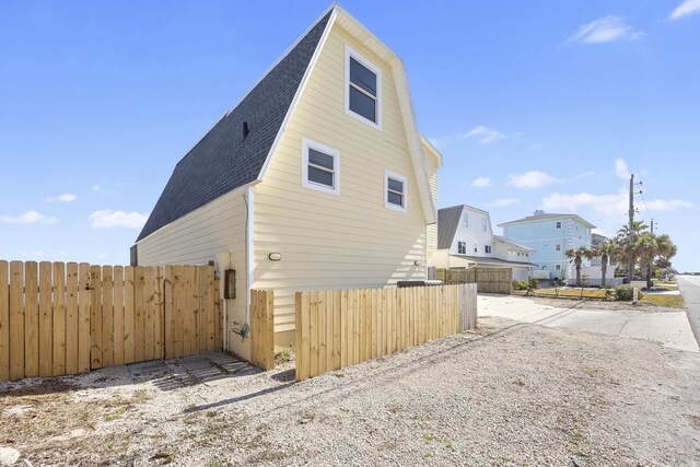 view of property exterior with a shingled roof and fence