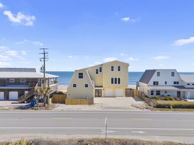 exterior space featuring a water view, fence, a garage, and driveway