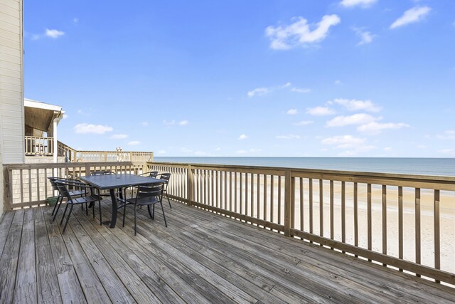 deck featuring outdoor dining space, a view of the beach, and a water view