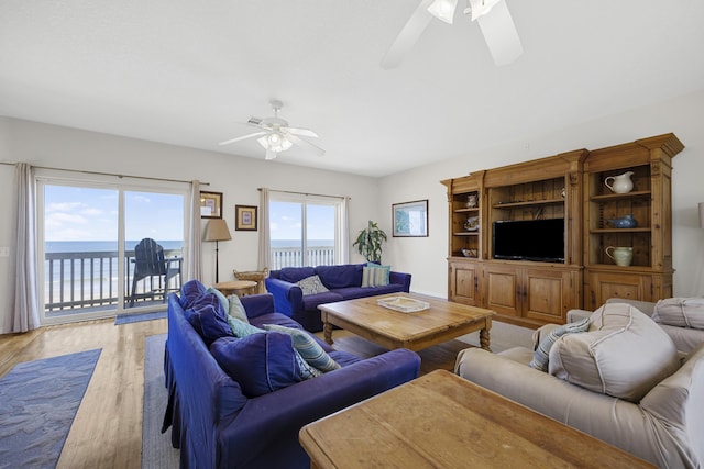 living room featuring a water view, light wood-style floors, and ceiling fan