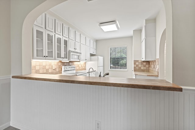 4515 Serena Cir, Saint Augustine, FL 32084 - kitchen featuring white appliances, decorative backsplash, a sink, a peninsula, and glass insert cabinets