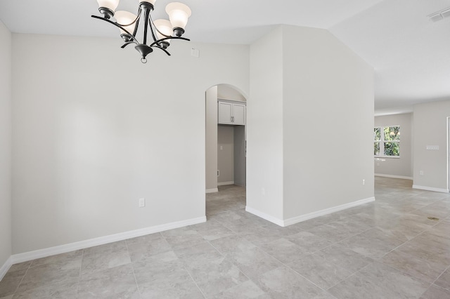 tiled empty room with a chandelier and vaulted ceiling