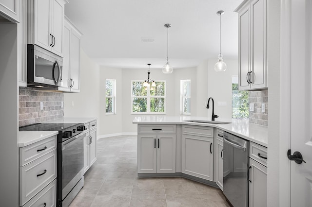 kitchen with backsplash, pendant lighting, sink, and appliances with stainless steel finishes