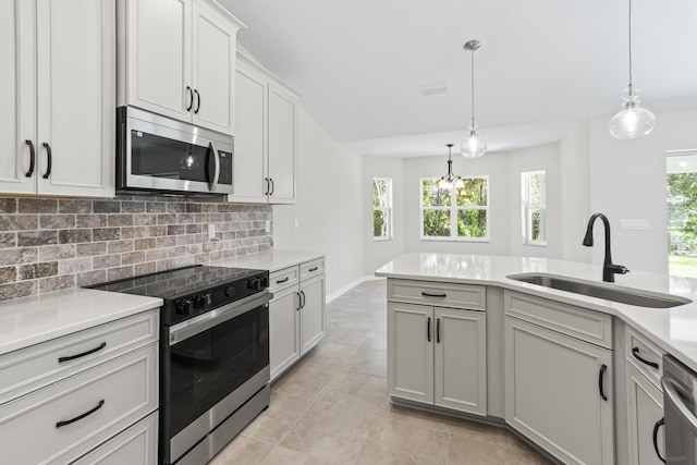 kitchen featuring sink, stainless steel appliances, tasteful backsplash, pendant lighting, and light tile patterned floors