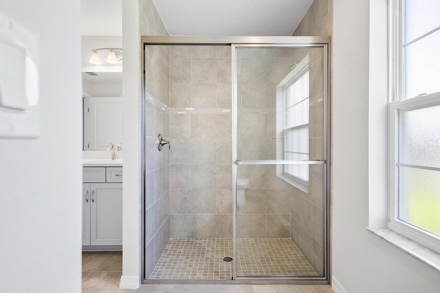 bathroom with tile patterned flooring, vanity, and walk in shower