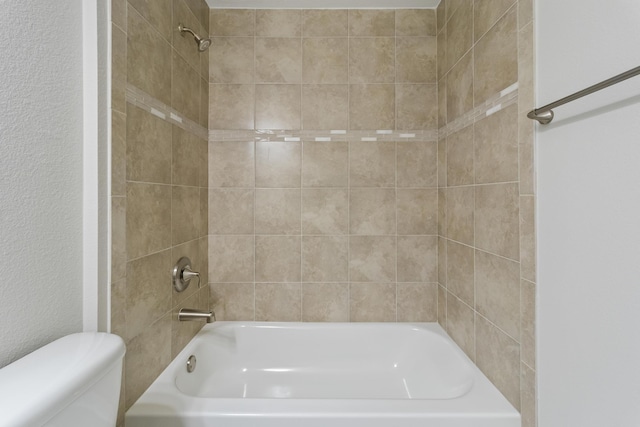 bathroom featuring tiled shower / bath combo and toilet