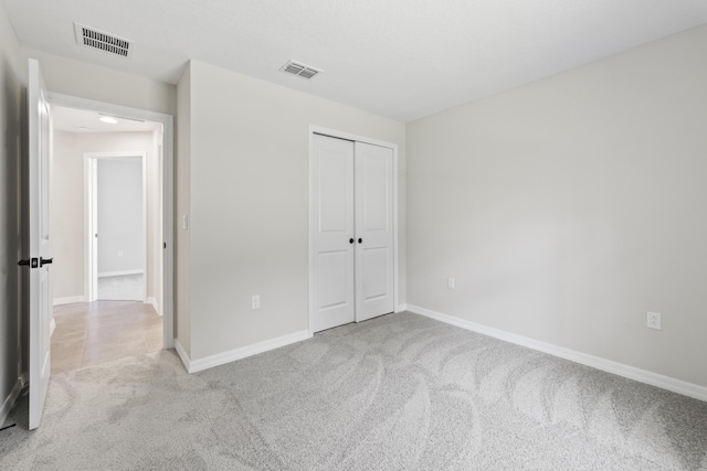 unfurnished bedroom with a closet and light colored carpet