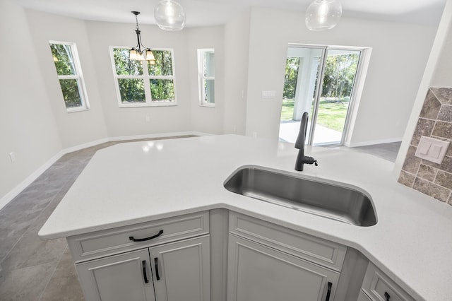 kitchen featuring gray cabinetry, sink, decorative light fixtures, and plenty of natural light