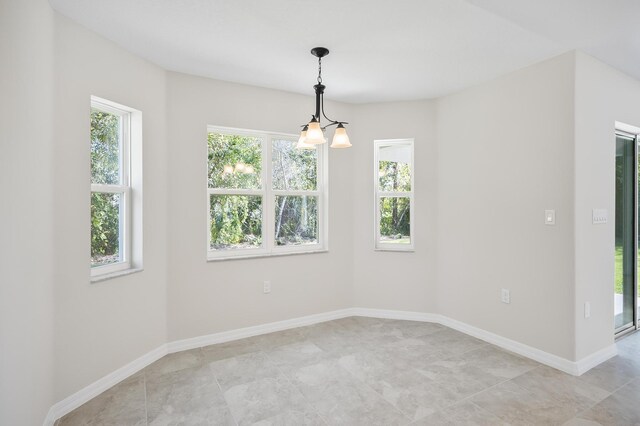 unfurnished room with a notable chandelier