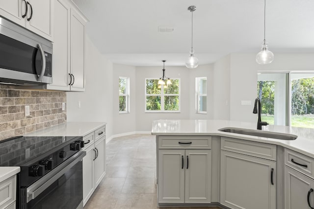 kitchen featuring decorative backsplash, sink, stainless steel appliances, and decorative light fixtures