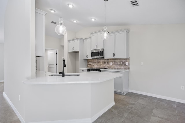 kitchen with stove, backsplash, vaulted ceiling, sink, and pendant lighting