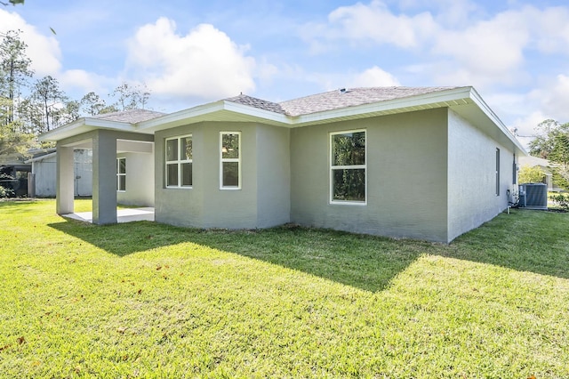 rear view of property with central AC unit and a yard