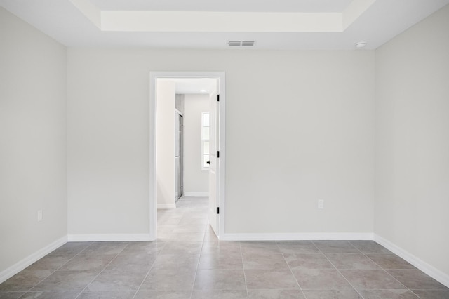 spare room featuring a raised ceiling and light tile patterned flooring