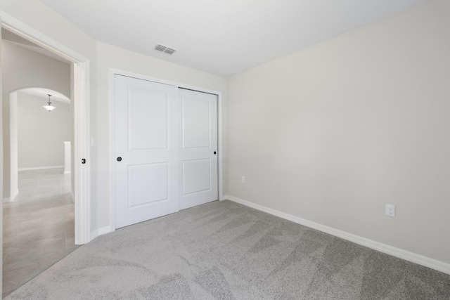 unfurnished bedroom with light carpet and a closet