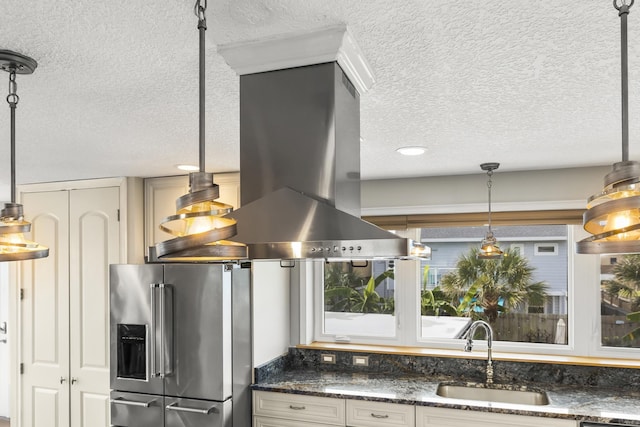 kitchen featuring a textured ceiling, high end fridge, decorative light fixtures, and sink