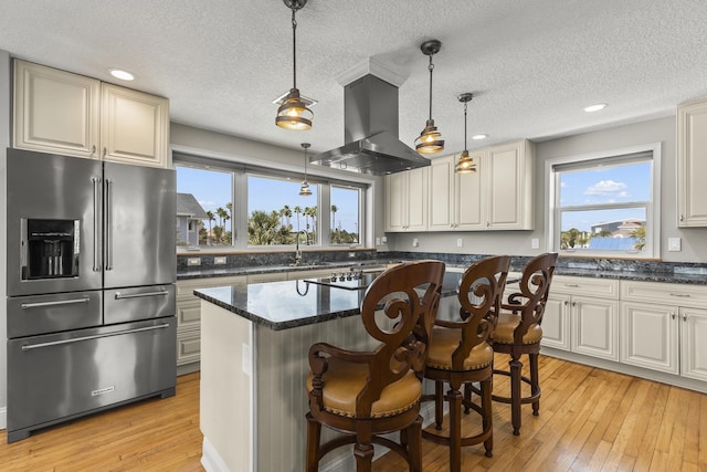 kitchen featuring hanging light fixtures, stainless steel appliances, island exhaust hood, a kitchen island, and light wood-type flooring