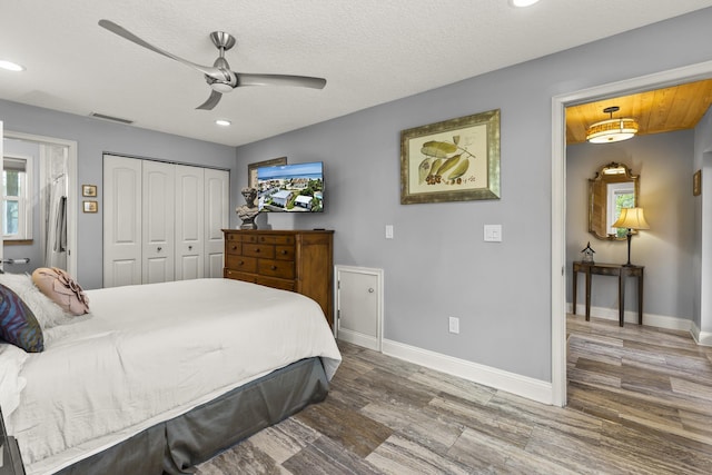 bedroom with ceiling fan, a closet, a textured ceiling, and hardwood / wood-style flooring