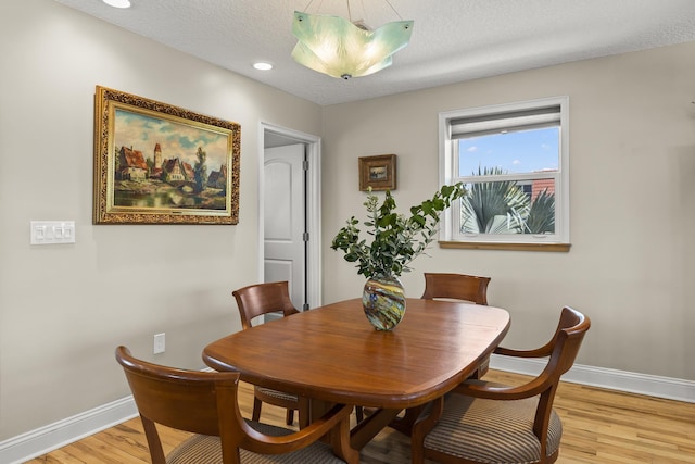 dining room with light wood-type flooring and a textured ceiling