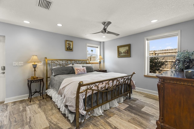 bedroom featuring hardwood / wood-style floors, ceiling fan, and a textured ceiling