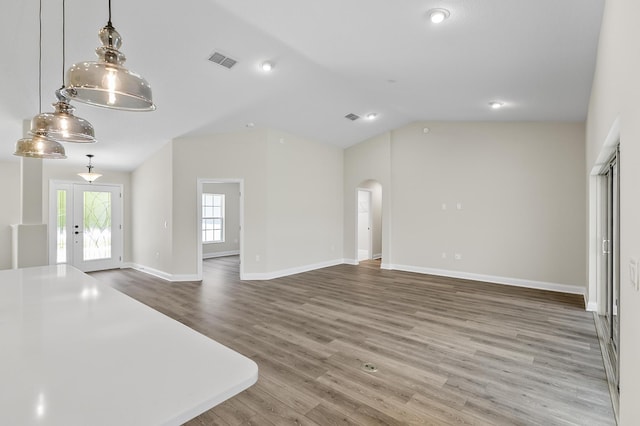 45 Laguna Forest Trl, Palm Coast, FL 32164 - unfurnished living room with arched walkways, wood finished floors, vaulted ceiling, baseboards, and french doors