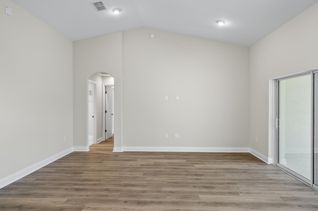 45 Laguna Forest Trl, Palm Coast, FL 32164 - empty room featuring arched walkways, wood finished floors, lofted ceiling, and baseboards
