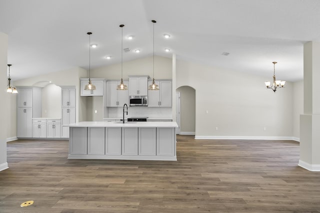 45 Laguna Forest Trl, Palm Coast, FL 32164 - kitchen featuring stainless steel microwave, arched walkways, a sink, light countertops, and an island with sink