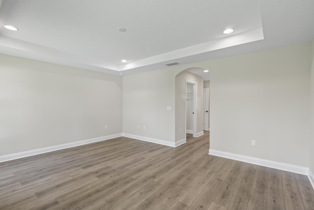 45 Laguna Forest Trl, Palm Coast, FL 32164 - empty room with a raised ceiling, arched walkways, recessed lighting, wood finished floors, and baseboards
