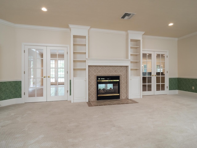 unfurnished living room with a fireplace, ornamental molding, light carpet, and french doors