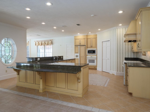 kitchen featuring stainless steel microwave, sink, white oven, kitchen peninsula, and a breakfast bar