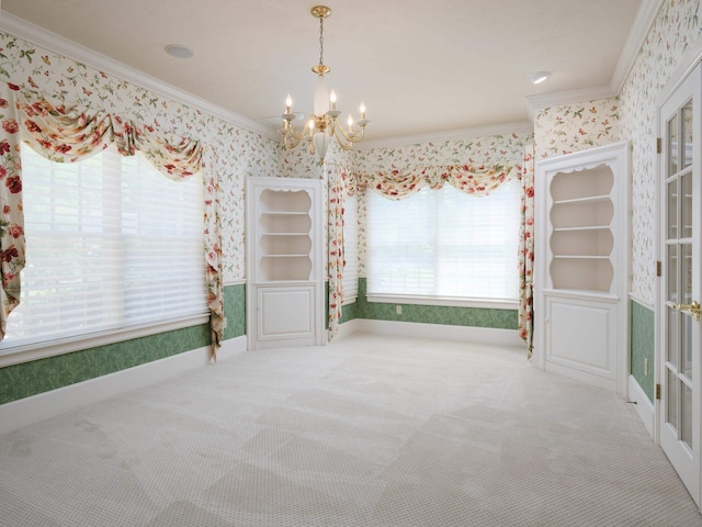 empty room featuring carpet floors, ornamental molding, and a notable chandelier