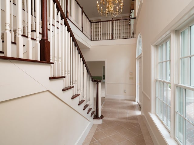 staircase featuring tile patterned flooring, a notable chandelier, and a towering ceiling