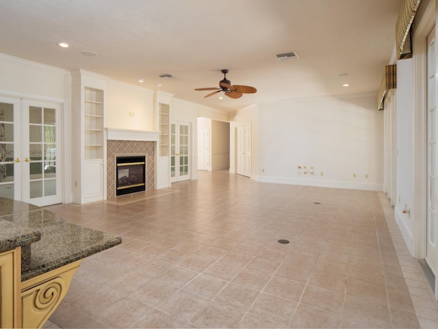 tiled living room featuring a tile fireplace, ceiling fan, french doors, and ornamental molding