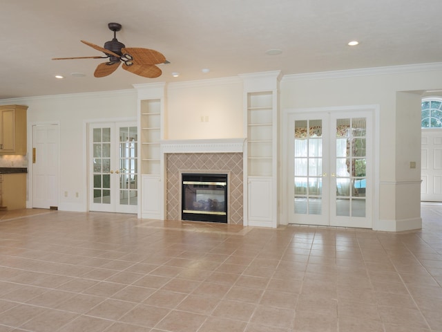 unfurnished living room with a tiled fireplace, crown molding, french doors, and light tile patterned flooring