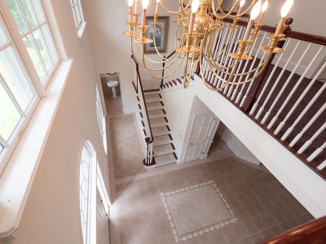 stairway with tile patterned floors and a chandelier