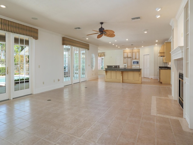 unfurnished living room featuring ceiling fan, light tile patterned floors, and ornamental molding