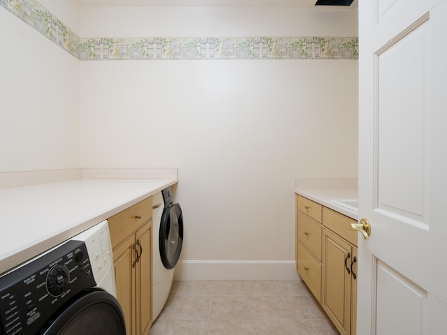 clothes washing area featuring washer and dryer, cabinets, and light tile patterned floors